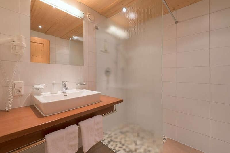 Dreibettzimmer mit Bad und Dusche im Hotel Bacherhof am Arlberg